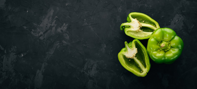 Fresh green pepper in a wooden box. On a black stone background. Top view. Free space for text.