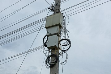 gray metal boxes on a pole with electric wires