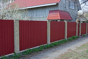 part of a red metal fence and a gate on the street