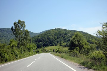 Road passing through gorgeous green hills - preserved environment. 