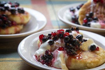 Homemade cheesecakes with sour cream and red and black currant sauce
