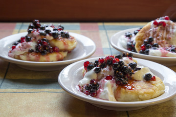 Homemade cheesecakes with sour cream and red and black currant sauce