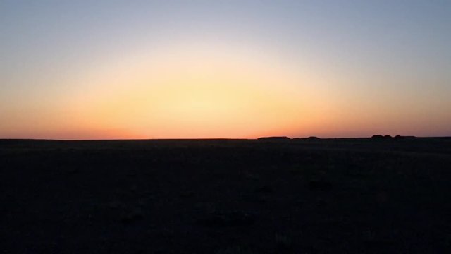 Sunset in the desert, boundless steppe, a car is passing by