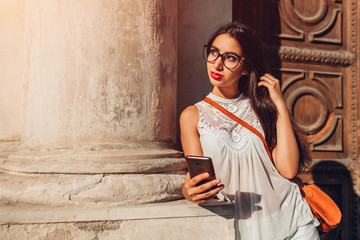 Beautiful tourist girl using smart phone outdoors. Middle-eastern woman searching for right way with navigator