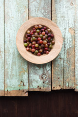 Organic berries. Healthy snack. Raw gooseberries in oak plate on rustic wooden background copyspace