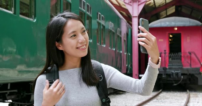 Woman taking photo on cellphone in train station