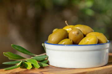 Bowl with green olives served as snack outdoor in olive tree garden