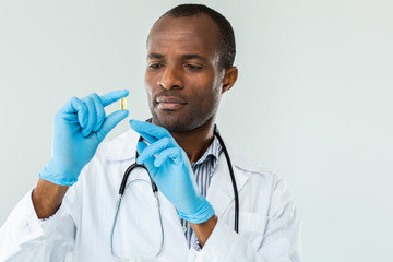 Close up of confident afro american doctor holding a pill