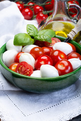 Italian soft cheese, young small balls mozzeralla cheese salad served with fresh basil, tasty ripe cherry tomatoes and Italian olive oil