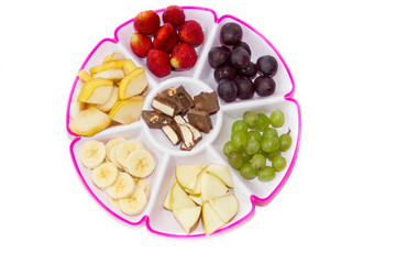 Fruit plate on a white background. Fruit and chocolate. Strawberry, banana, chocolate, grapes, apple, pear.