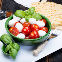 Italian soft cheese, young small balls mozzeralla cheese salad served with fresh basil, tasty ripe cherry tomatoes and Italian olive oil