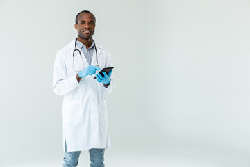 Cheerful afro american doctor standing against white background