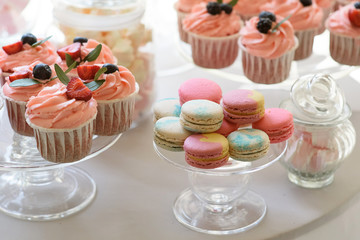 Round table with luxurious cupcakes and macaroons