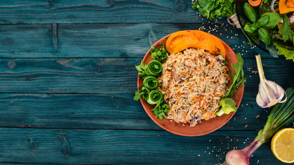 Plov Rice with meat and vegetables on a plate. Uzbek cuisine. On a wooden background. Top view. Copy space.