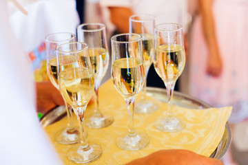 A close-up of a round tray with champagne glasses for guests