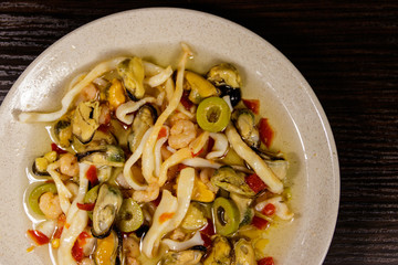 Seafood salad with shrimp, squid and mussels on wooden table