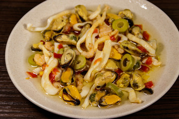 Seafood salad with shrimp, squid and mussels on wooden table