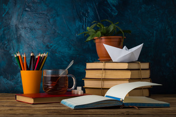 A Pile of Books, A Cup of Hot Tea, A Paper Boat, Colored Pencils
