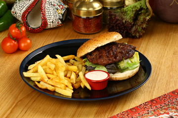 Burger with french fries on black plate
