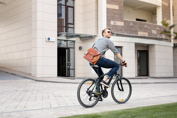 Eco friendly. Happy positive man riding a bicycle while going to work - obrazy, fototapety, plakaty