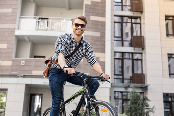 Physical activity. Joyful nice man staying healthy while riding a bicycle