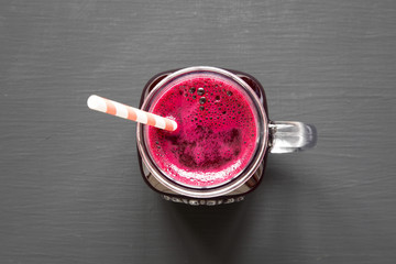 Beetroot smoothie in glass jar mug over black background, view from above. Flat lay, overhead. Closeup.