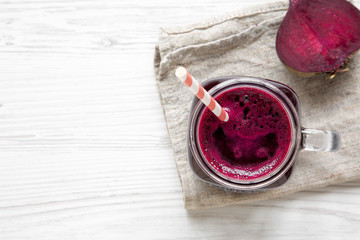 Beetroot smoothie in glass jar mug over white wooden background, view from above. Flat lay, overhead. Copy space and text area.