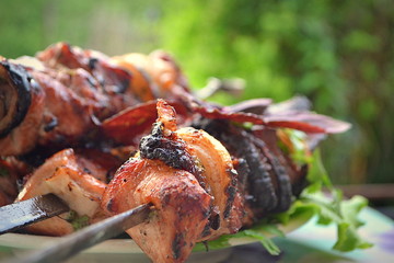Appetizing pork shish kebab on a grill on a skewer with a back blur background.