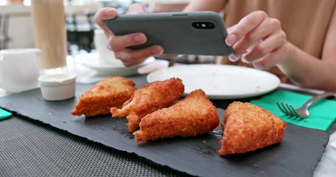Woman taking photo on fried chicken wing