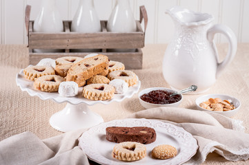 Italian Cookies with jam, almonds, milk bottles and pitcher on a cloth tablecloth.