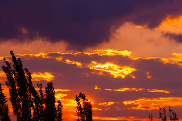 Landscape with dramatic light - beautiful golden sunset with saturated sky and clouds.