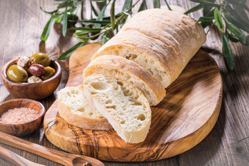 Olives and feta cheese, bread ciabatta,  on olive wood cutting board - obrazy, fototapety, plakaty