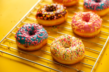 Variety of colorful tasty glazed donuts on a colored background