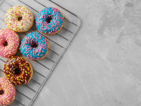 Colorful tasty glazed donuts on a grey background