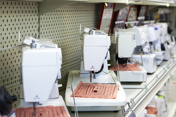 Electric sewing machines on store shelf, side view, shallow depth of field.