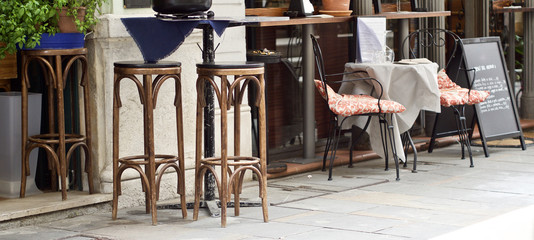 Hölzerne Tische und Sesseln in einem Gastgarten 