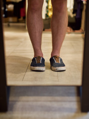 Junger Mann betrachtet sich in einem Spiegel in einem Modegeschäft