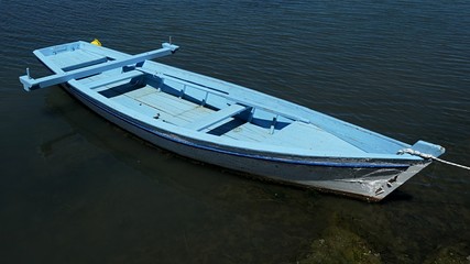 Slim light blue fishing boat with vertical oar support 