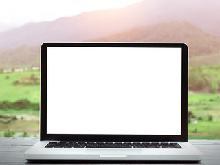 Laptop computer with blank white screen on table,nature background.