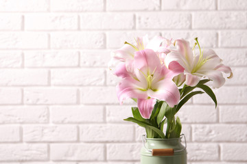 Beautiful blooming lily flowers near brick wall