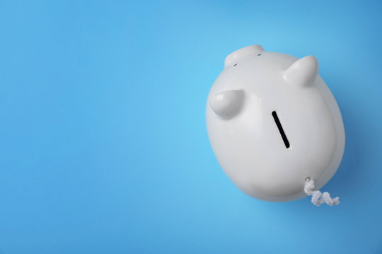 White piggy bank on color background, top view