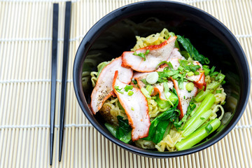 Yellow noodles served with sliced red pork