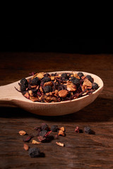 tea and natural additives in wooden spoons, on old wooden table. Selective focus