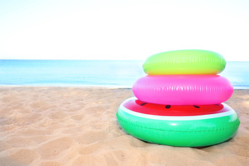 Pile of colorful inflatable rings on sand near sea