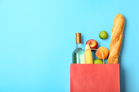 Flat lay composition with shopping bag and products on color background
