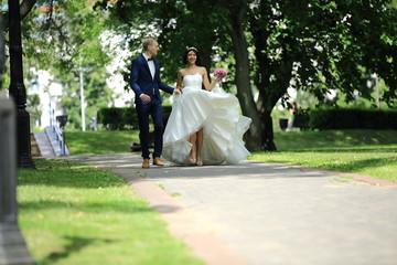 Fototapeta premium back groom and bride walking along the alley on the background of trees