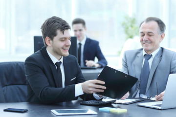 adult businessman discussing financial documents with a young colleague.