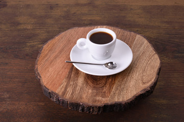 Single white cup of espresso coffee on an aged wooden platform.