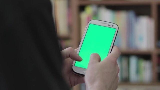 Close up of hands sms texting and scrolling on smartphone on green screen. Man messaging and typing on smart phone for business incrustation