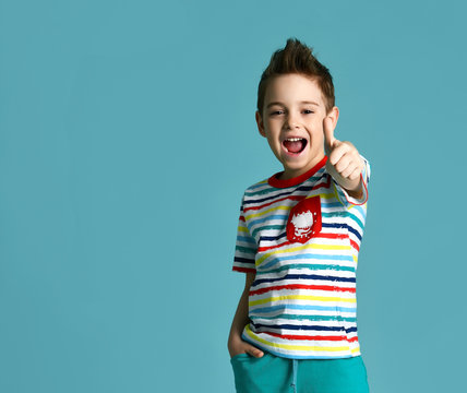 boy in blue yellow stripes tshirt show thumbs up sign positive smiling yelling on light mint background